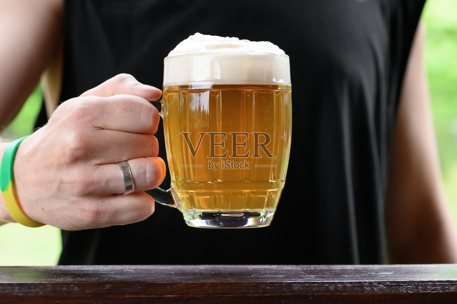 一个男人手持啤酒杯，正在喝酒照片摄影图片