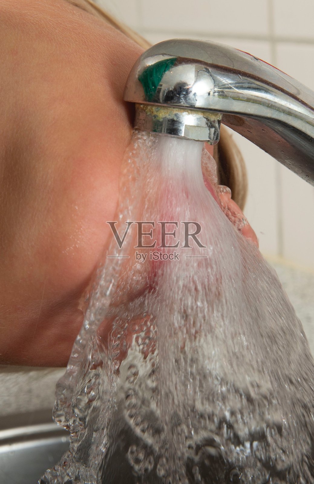 在厨房水槽的水龙头喝水。照片摄影图片