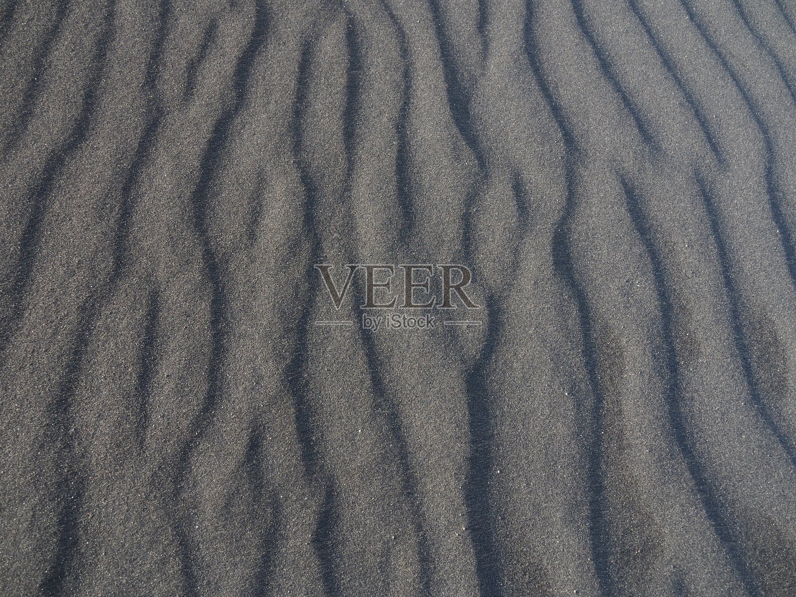 波浪状的黑色沙子图案在自然中形成了一个被风塑造的有纹理的表面照片摄影图片