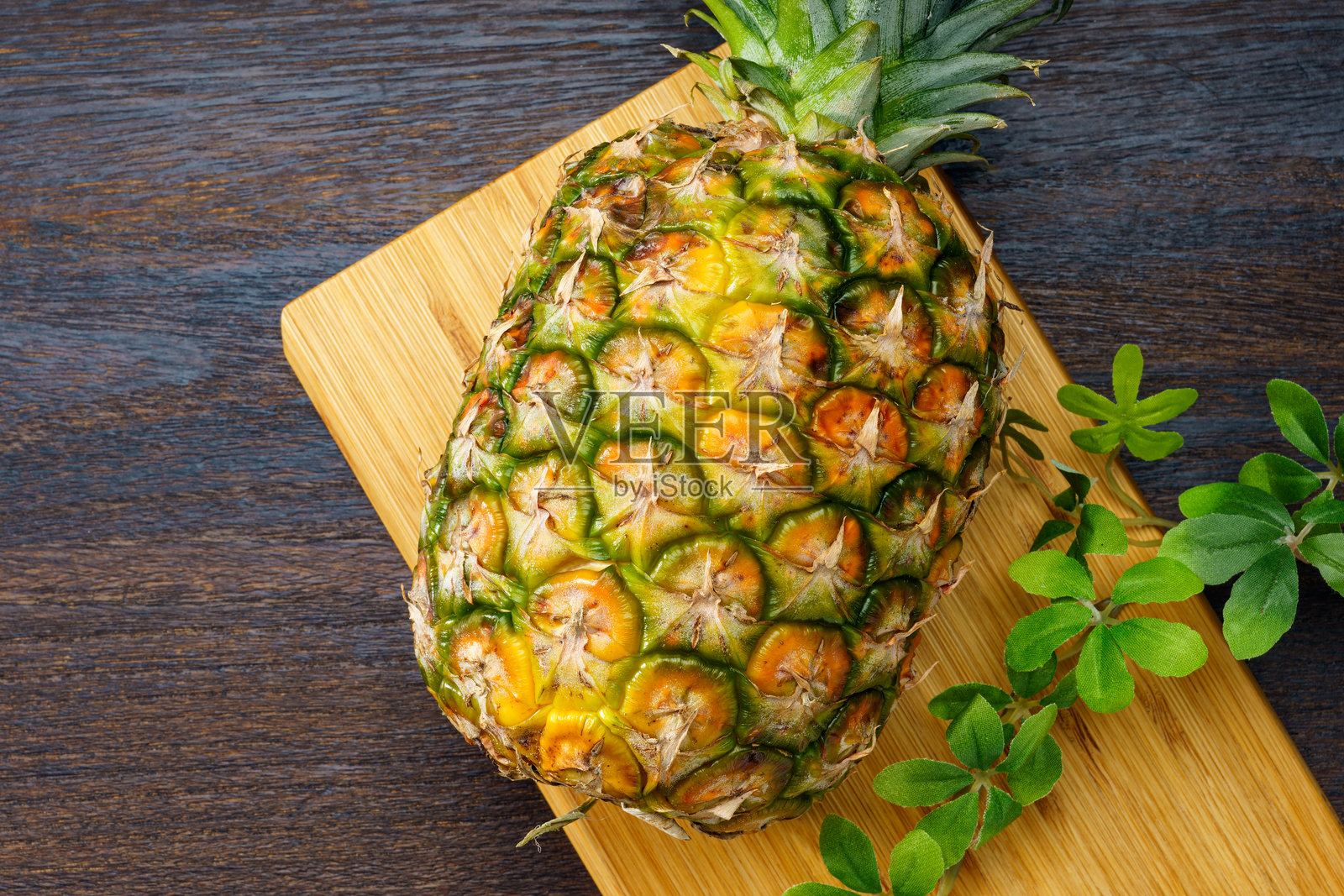 新鲜菠萝和木桌上的切菜板照片摄影图片