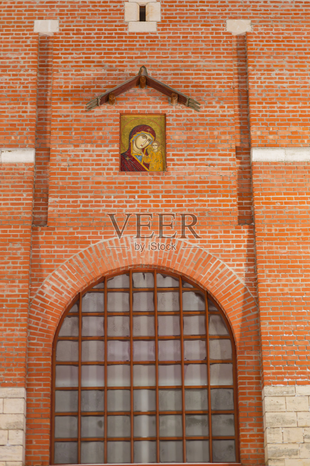 一座带窗户的砖砌建筑，旁边是一幅女人抱着孩子的画。下诺夫哥罗德克里姆林宫的景象。照片摄影图片