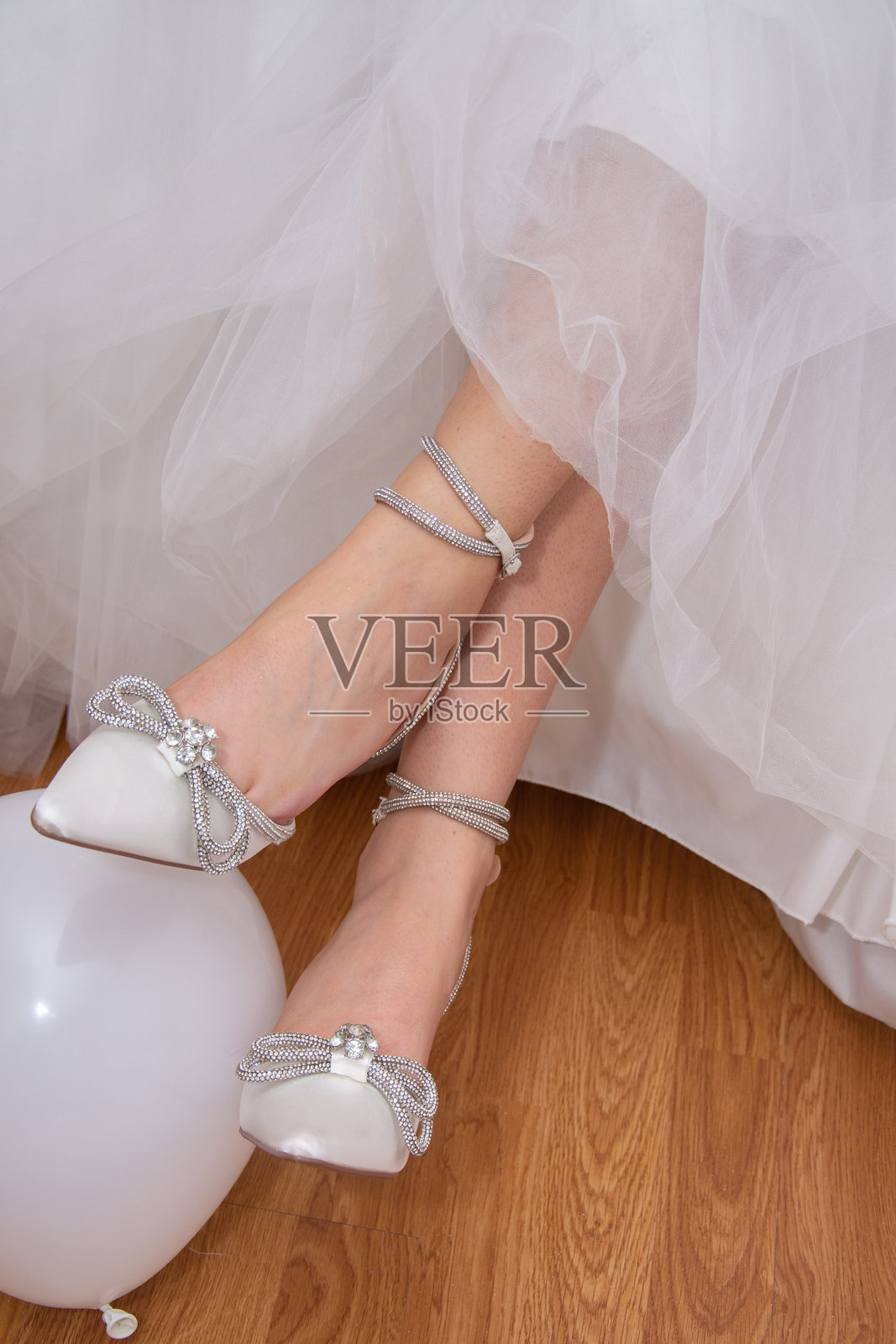 新娘在她娇嫩的脚上穿上白色鞋子。照片摄影图片