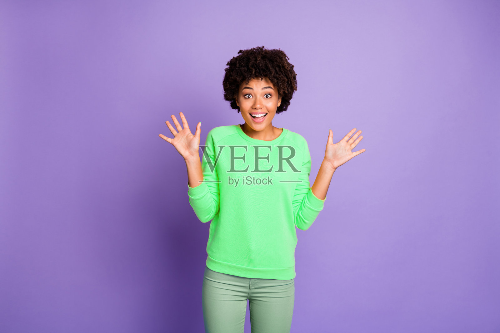 她是一位迷人、愉快、充满活力的波浪卷发女孩，面带惊讶的表情，背景为紫色和淡紫色的柔和色调。照片摄影图片