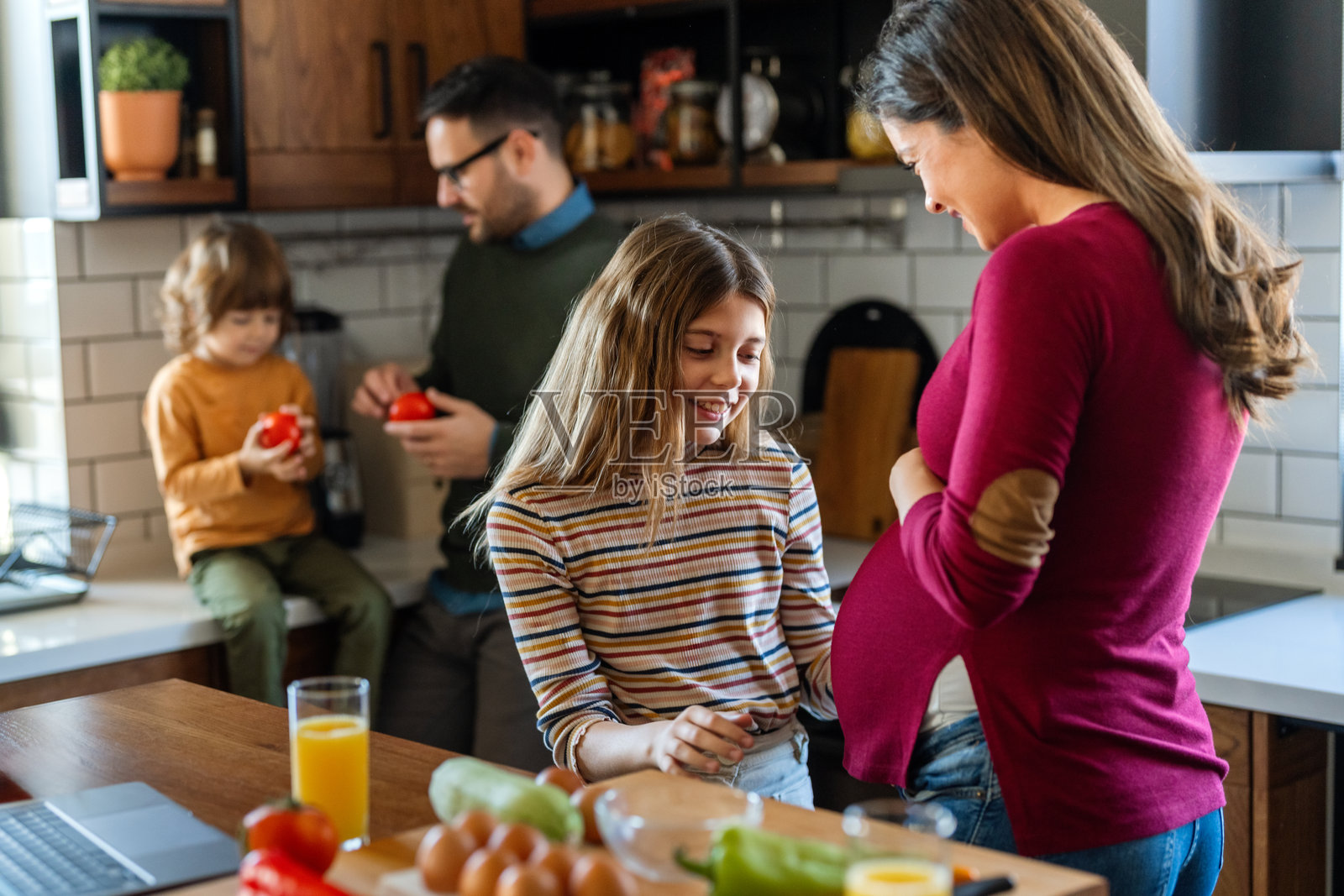 怀孕的母亲与女儿温柔相拥，父亲和儿子在家中享受快乐的白天时光照片摄影图片