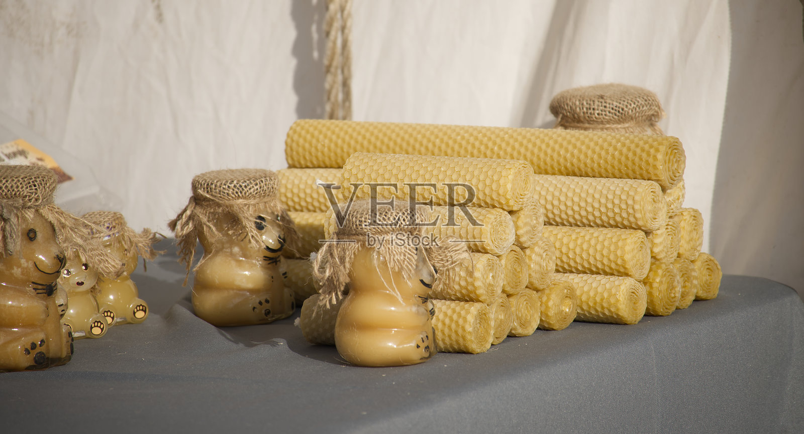 手工蜂蜜蜡烛和装饰性蜂蜜罐在桌子上展示照片摄影图片