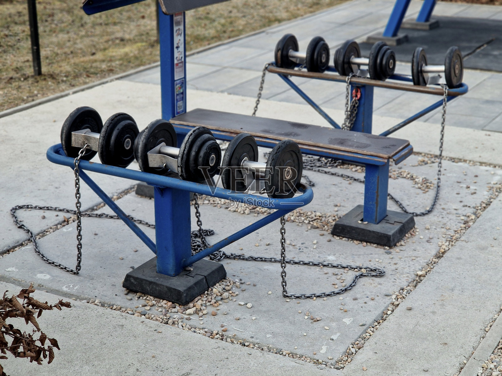 户外健身房，配备大量哑铃和举重长凳。每件设备都用链条锁住以防盗窃。城市或办公楼周围的公共公园对员工有益。照片摄影图片