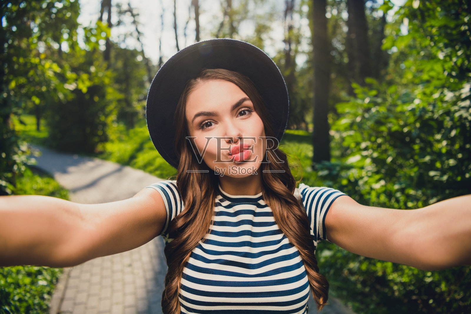 迷人、开朗、调皮的女孩在户外休息，送出空气之吻，享受闲暇时光。照片摄影图片