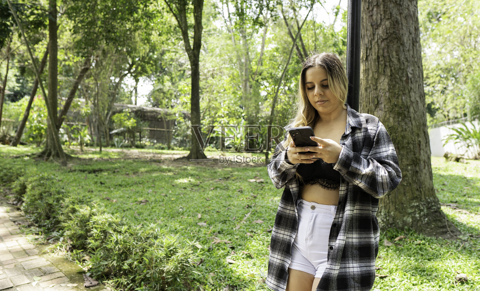 公园里拿着手机的美丽女性照片摄影图片