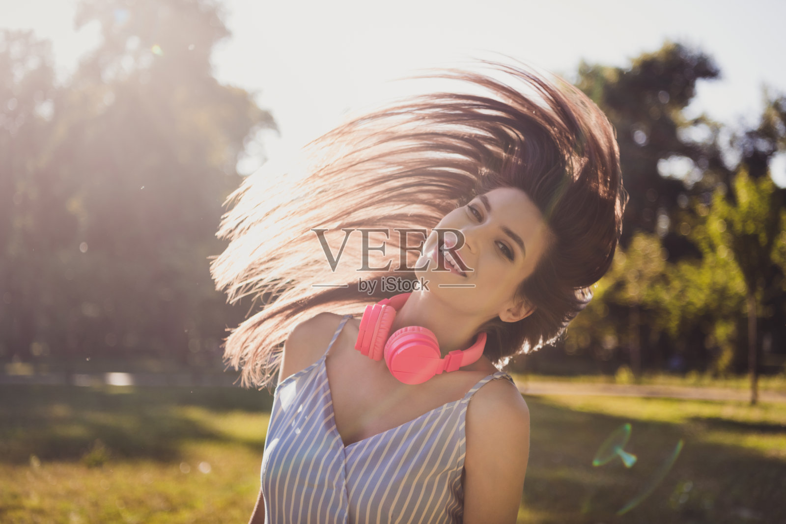 迷人、快乐、无忧无虑的女孩在户外享受自由时光，听着热门单曲，甩着头发，玩得很开心。照片摄影图片