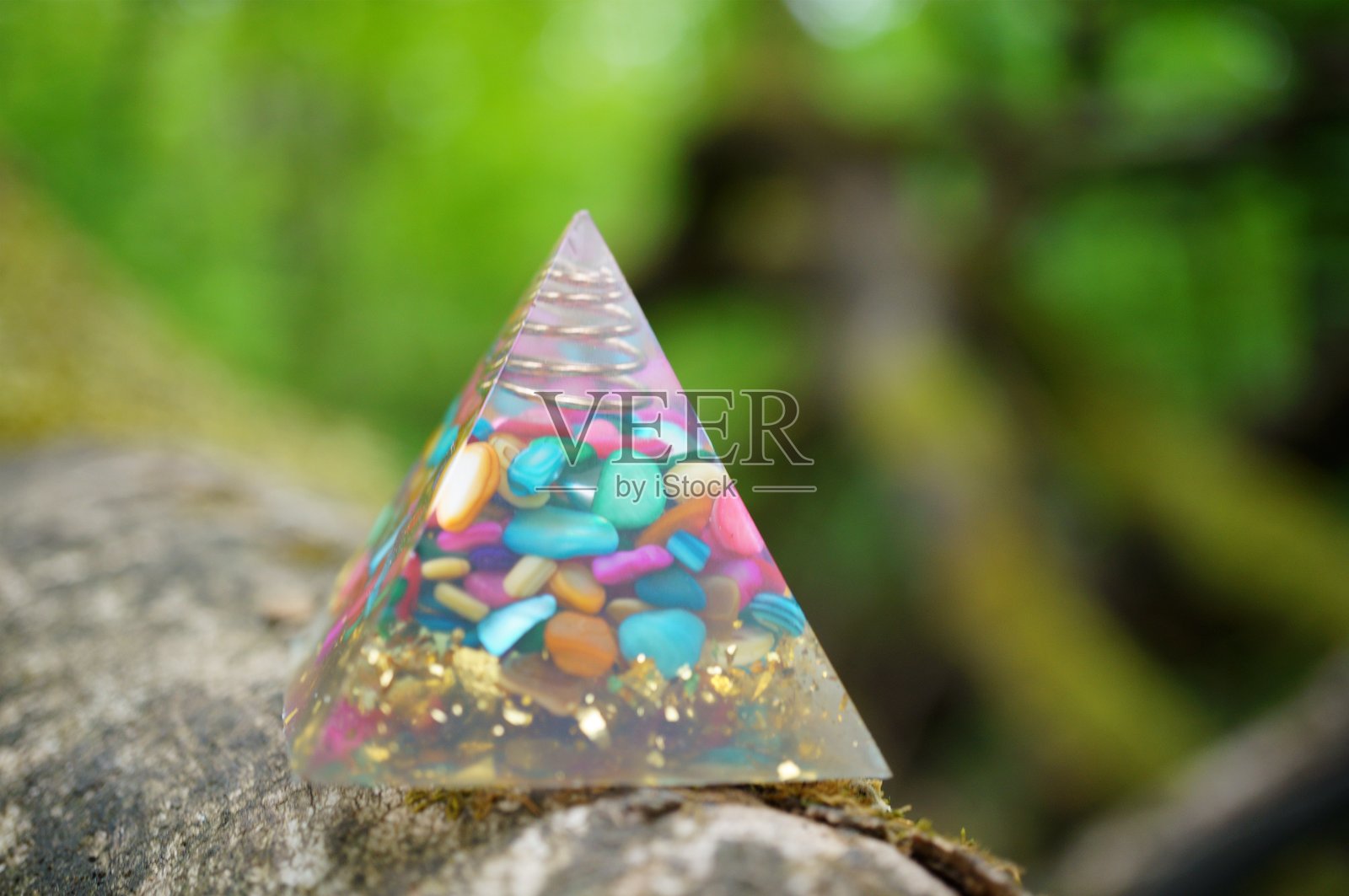 一个玻璃金字塔的雕像，里面装有彩色石头。彩色玛瑙。一个强大的风水象征。照片摄影图片