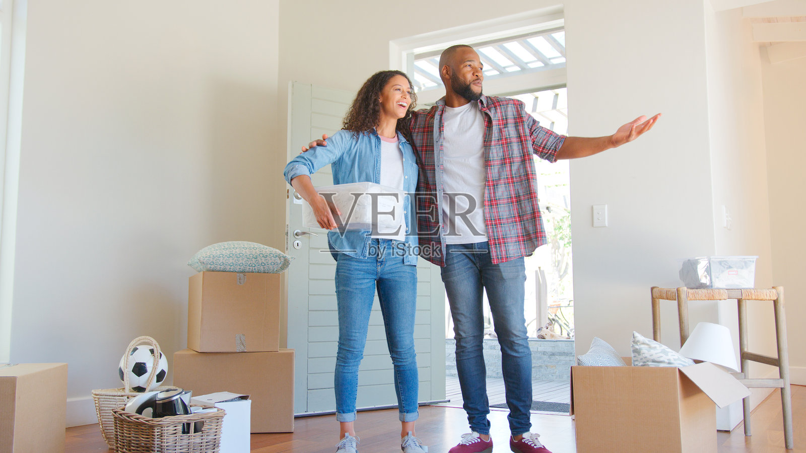 热爱彼此的情侣在搬家日站在新家中，周围是纸箱。照片摄影图片