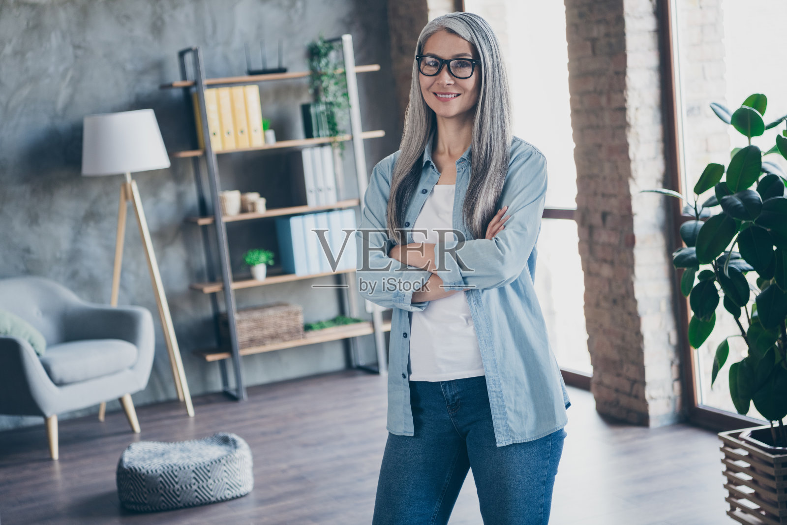 美丽自信的退休女士在家办公室内双臂交叉站立于工作台前照片摄影图片