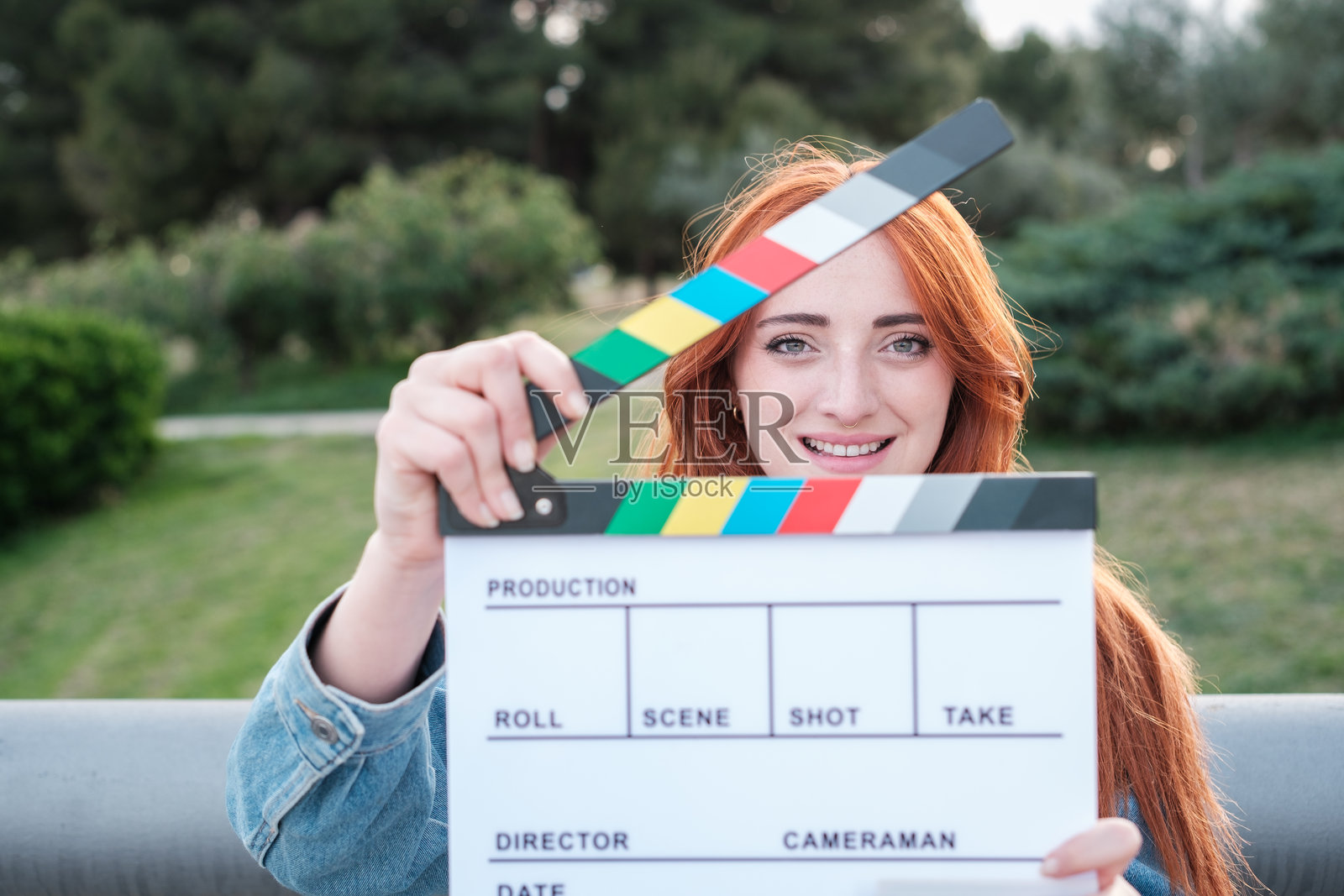 户外微笑的红发年轻女性手持电影拍板。概念：生活方式，微笑，户外照片摄影图片
