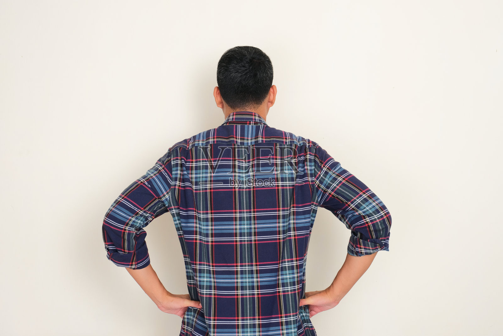 一个男人背对着站立，双手放在腰间。照片摄影图片