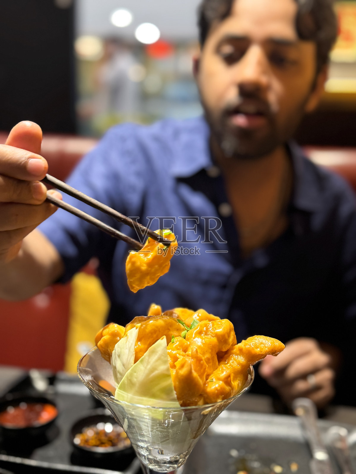 筷子夹着脆皮天妇罗虾/金黄炸海鲜的鸡尾酒杯，配有辣酱，正宗亚洲美食照片摄影图片