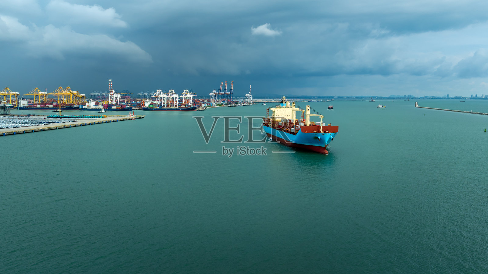 航拍前视图显示货运集装箱船在雨季从商业港口出发，进行货物物流的商业和工业运输服务，以通过船舶货运进行进出口。照片摄影图片