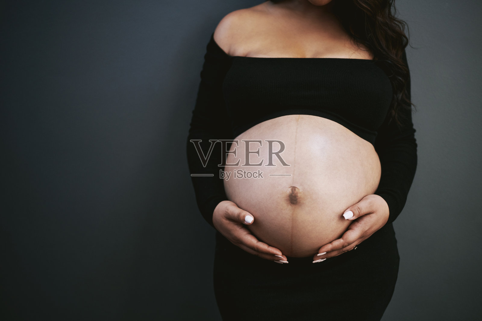 孕妇的手轻轻托着她的肚子照片摄影图片