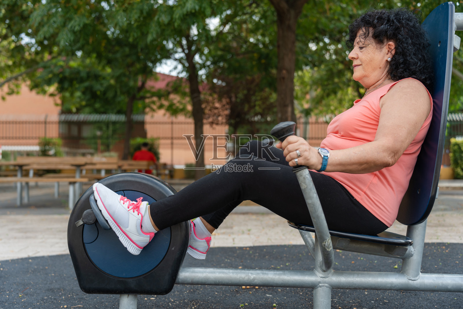 老年女性在公园使用健身器械锻炼腿部照片摄影图片