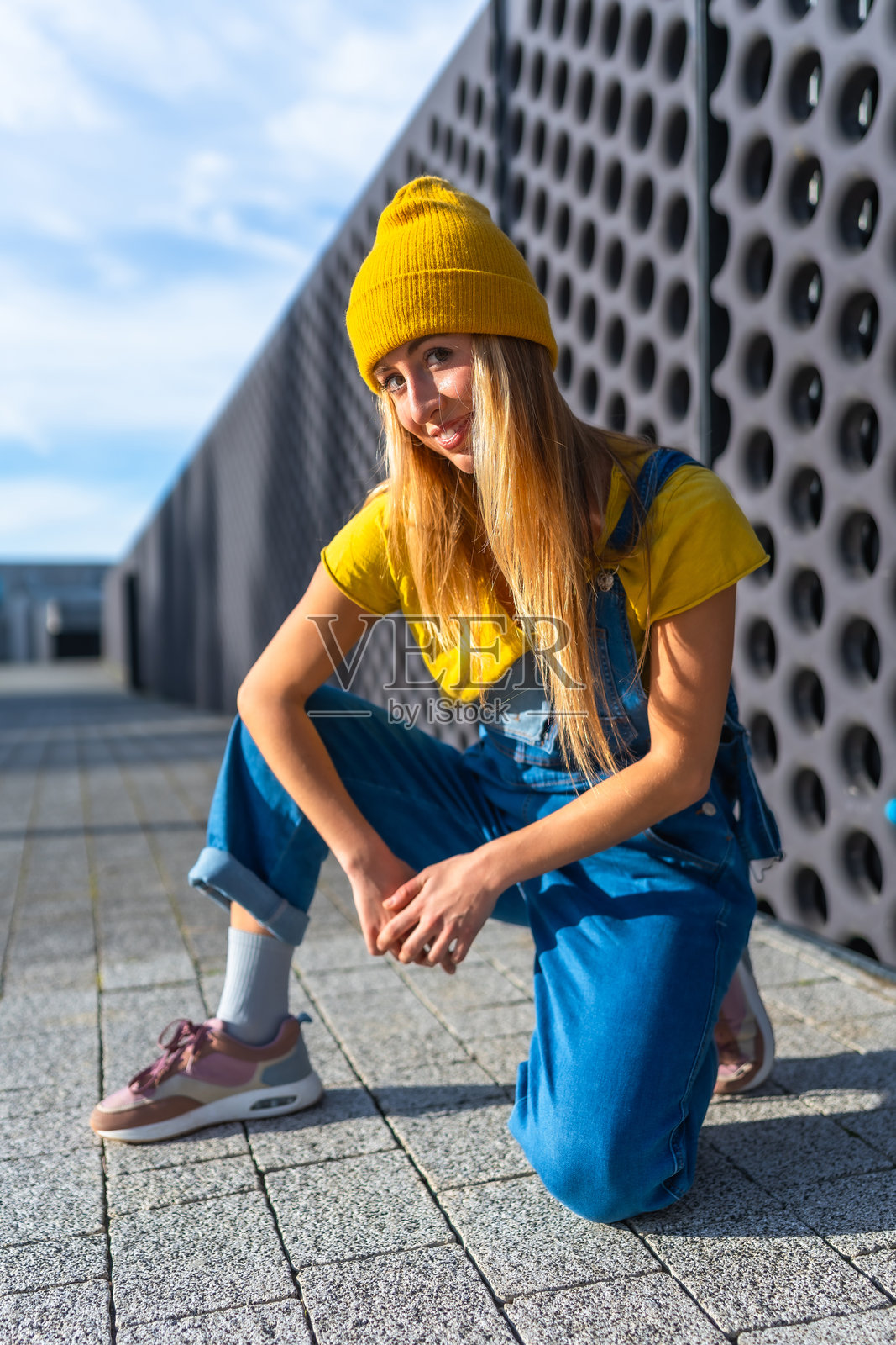 年轻的金发舞者在城市环境中摆姿势，穿着休闲服装照片摄影图片