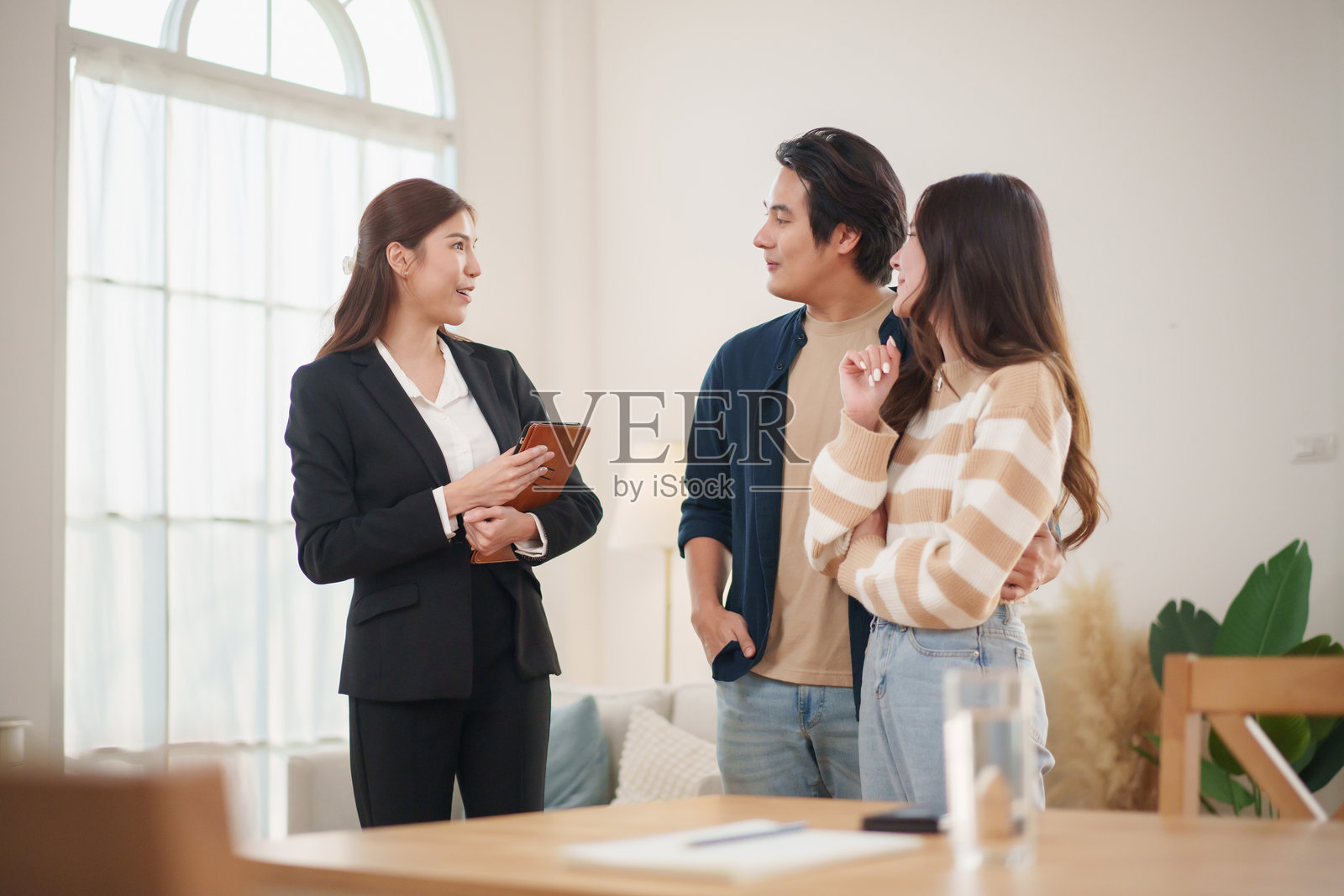 亚洲夫妇在现代居住空间中与房地产经纪人讨论财务规划，进行房屋参观。照片摄影图片