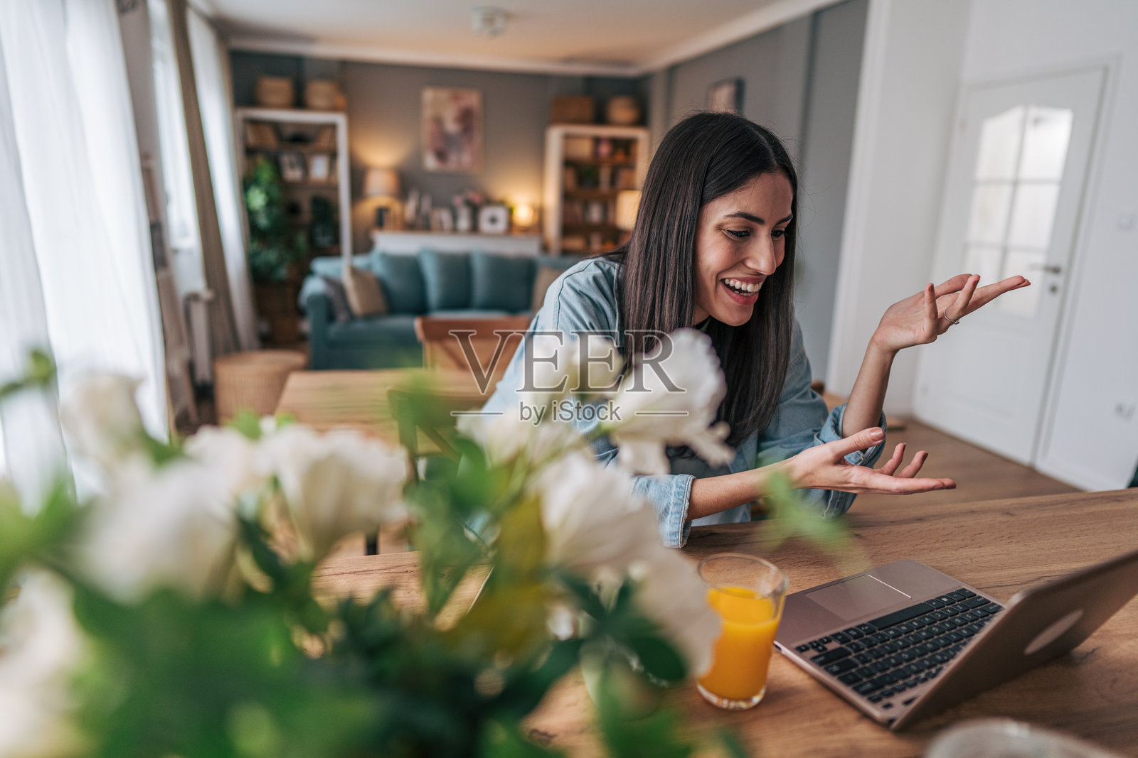 年轻女性在家工作，正在通过笔记本电脑进行视频通话照片摄影图片