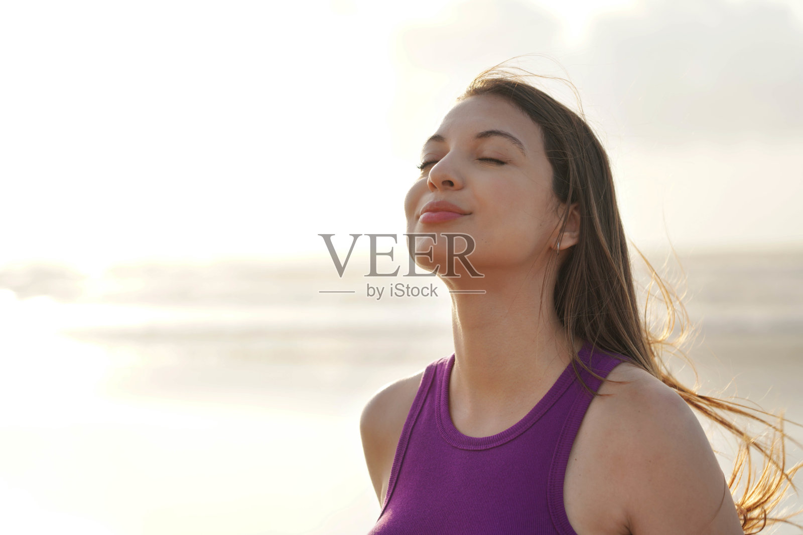 年轻女性在海滩上享受日落微风的特写镜头照片摄影图片