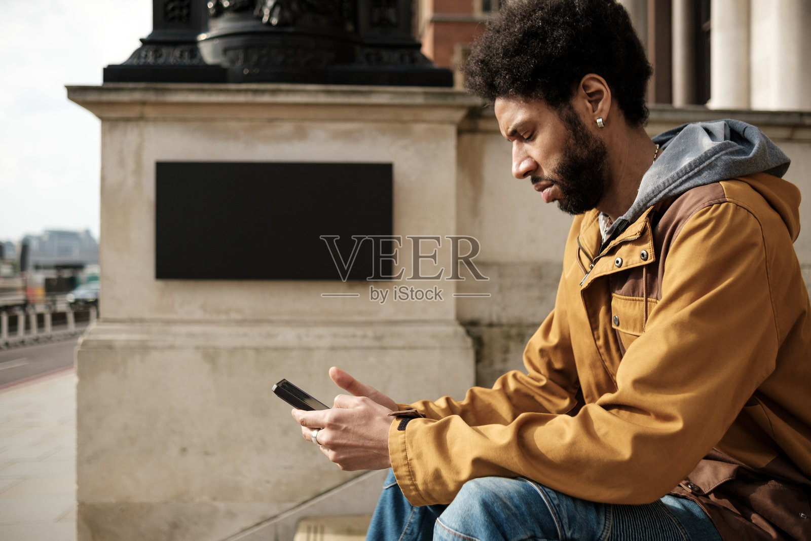 游客坐在伦敦的台阶上使用智能手机照片摄影图片