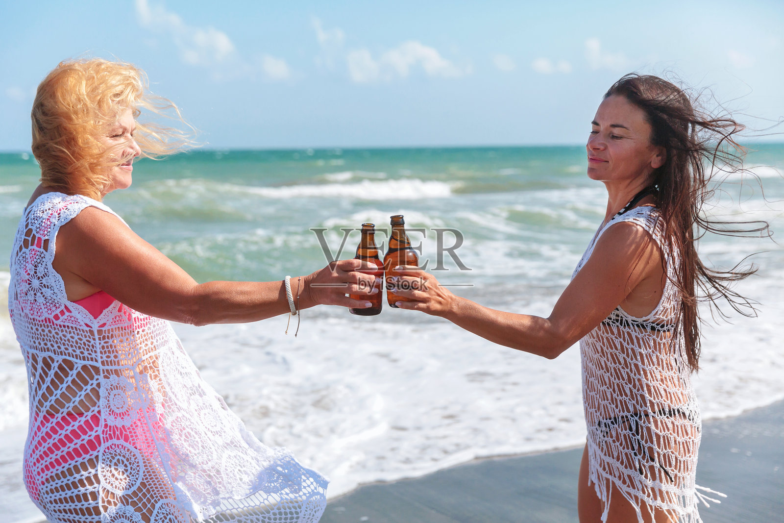 女性在海滩上享受夏日饮品照片摄影图片