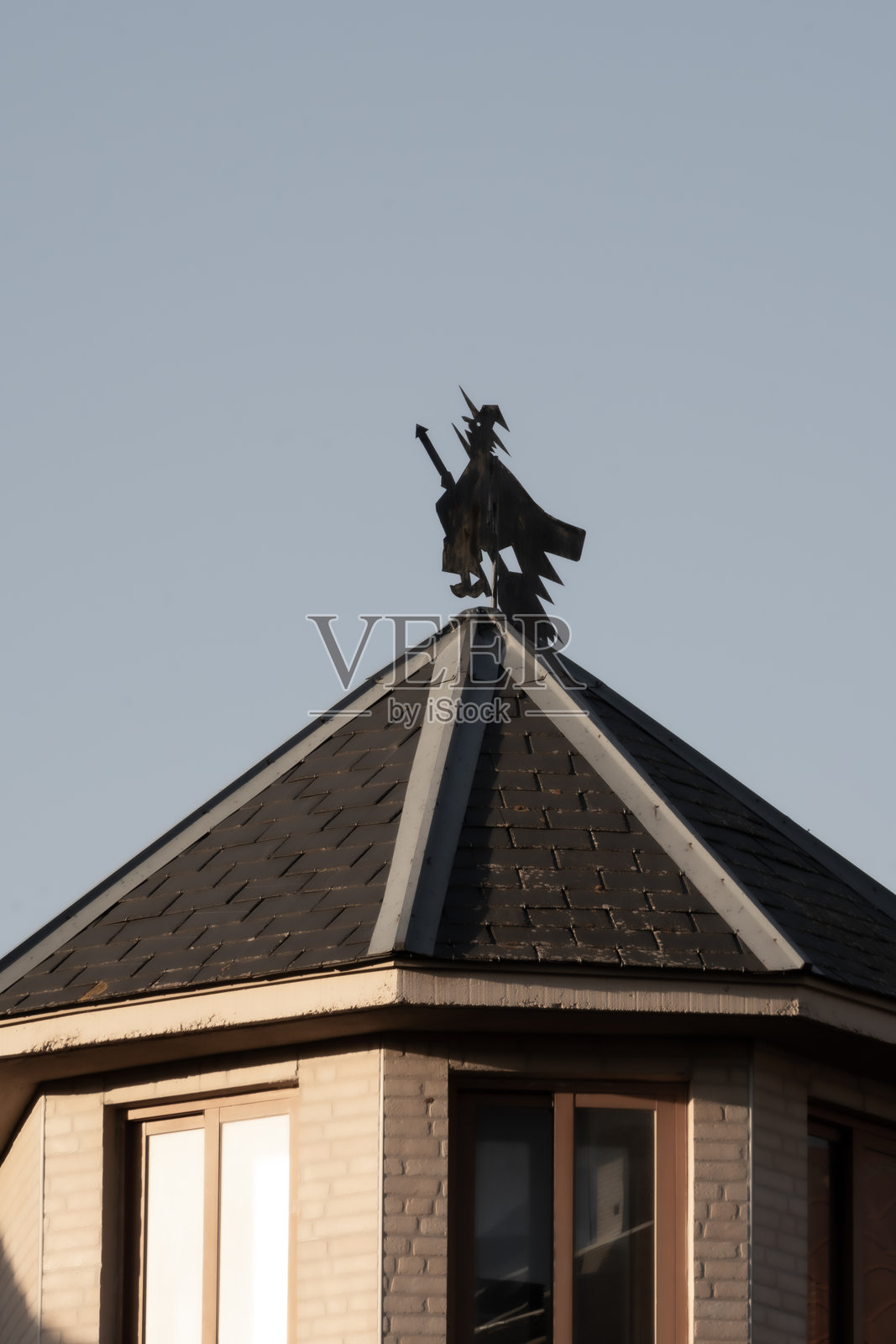 夜幕降临时，奇特房屋屋顶上的女巫风向标照片摄影图片