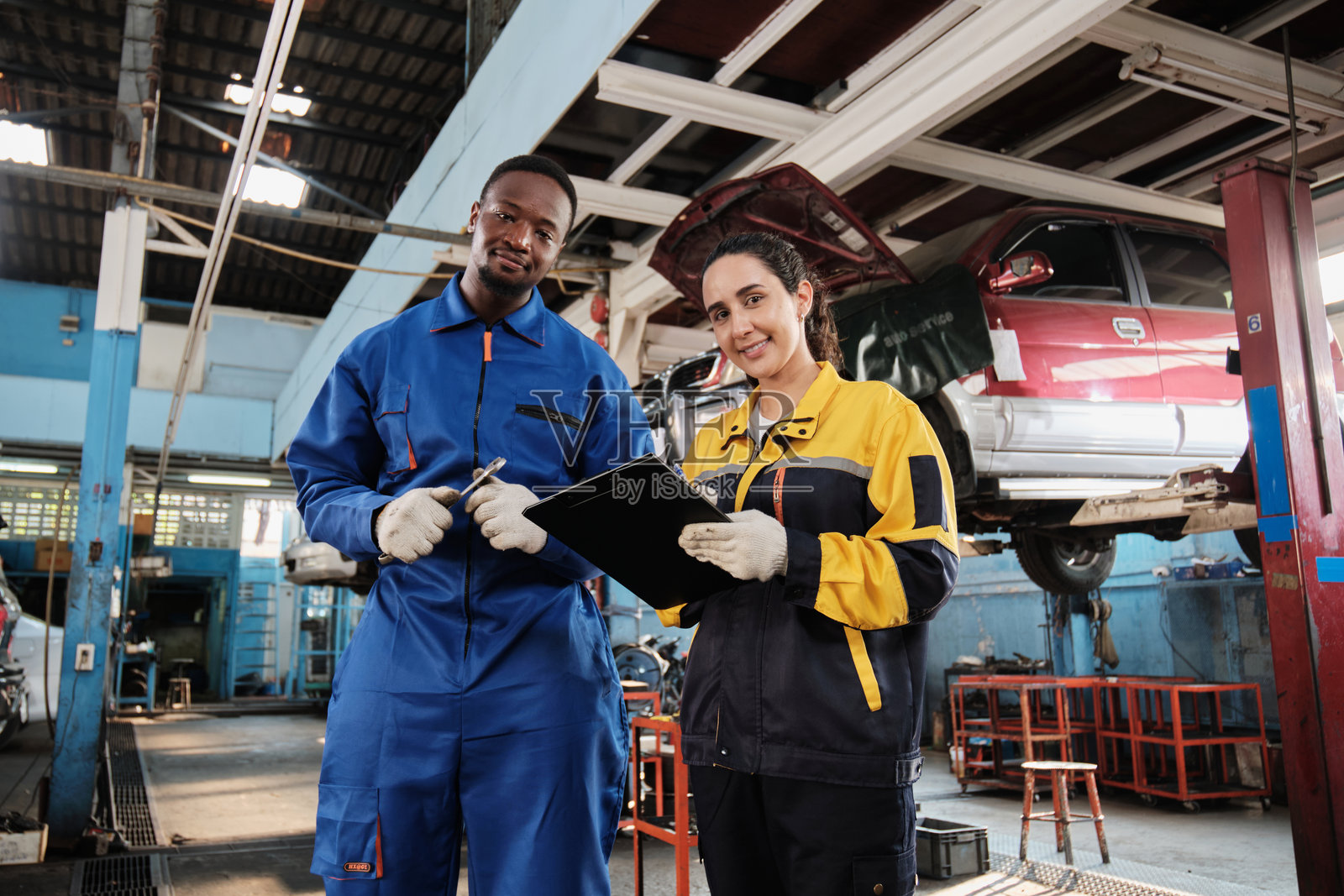 快乐的机械师团队，在修车车库中面带微笑。照片摄影图片