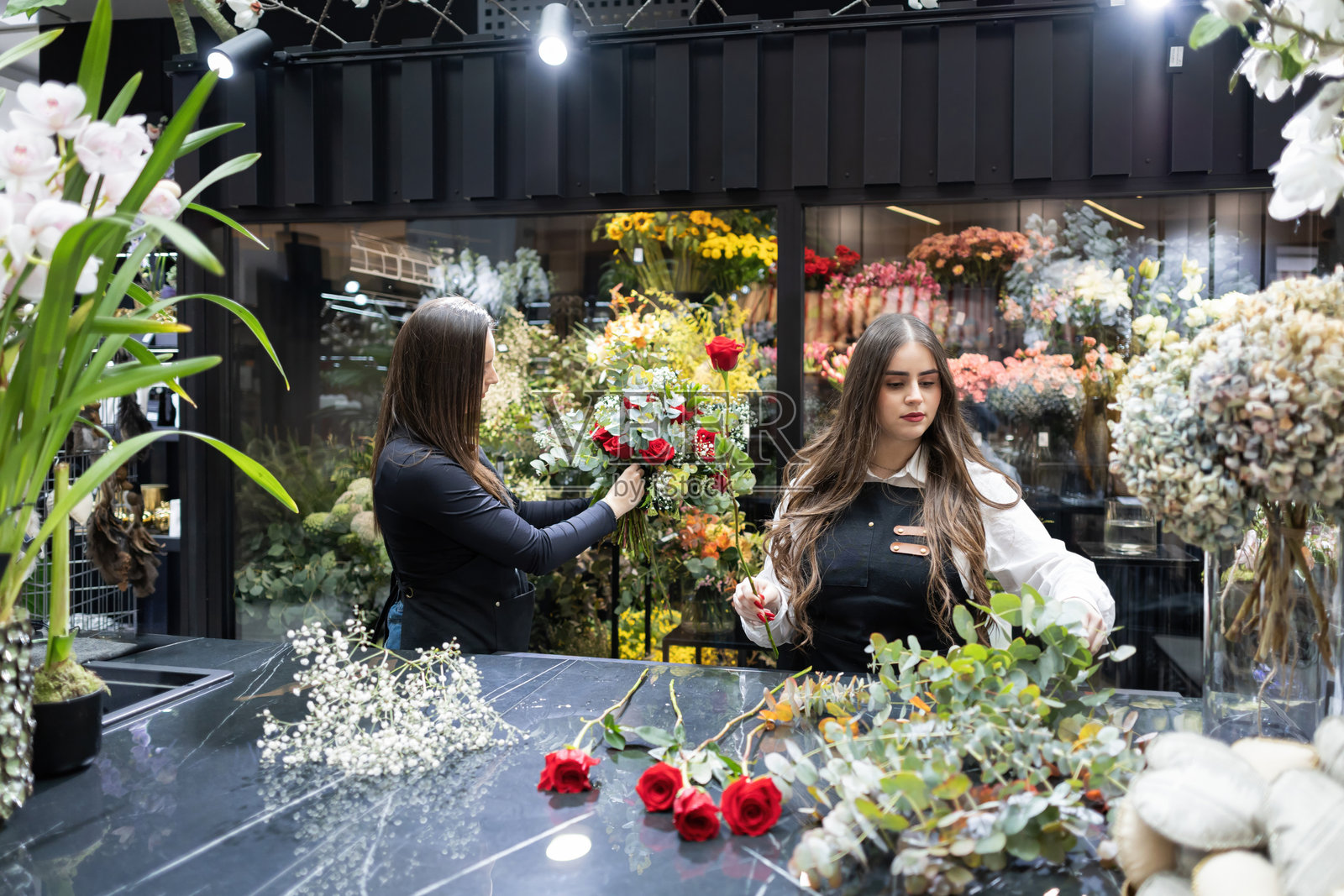 花店里的花艺师正在整理红玫瑰和桉树枝照片摄影图片