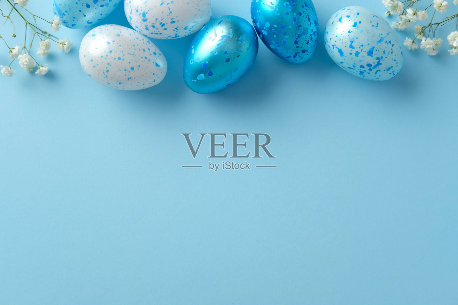 蓝白相间的复活节彩蛋，上面有白色花朵，背景为浅蓝色。平铺，俯视，留白空间。照片摄影图片