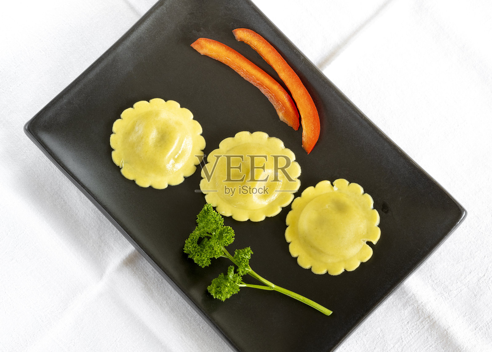 三颗饺子在黑色盘子里照片摄影图片