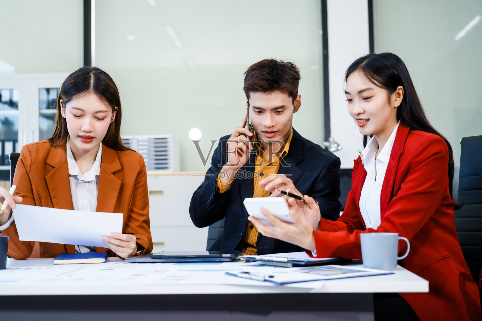 三位亚洲商务专业人士在会议室聚集，进行年度会议，讨论战略目标、未来预测，同时提出想法，参与企业增长的决策。照片摄影图片