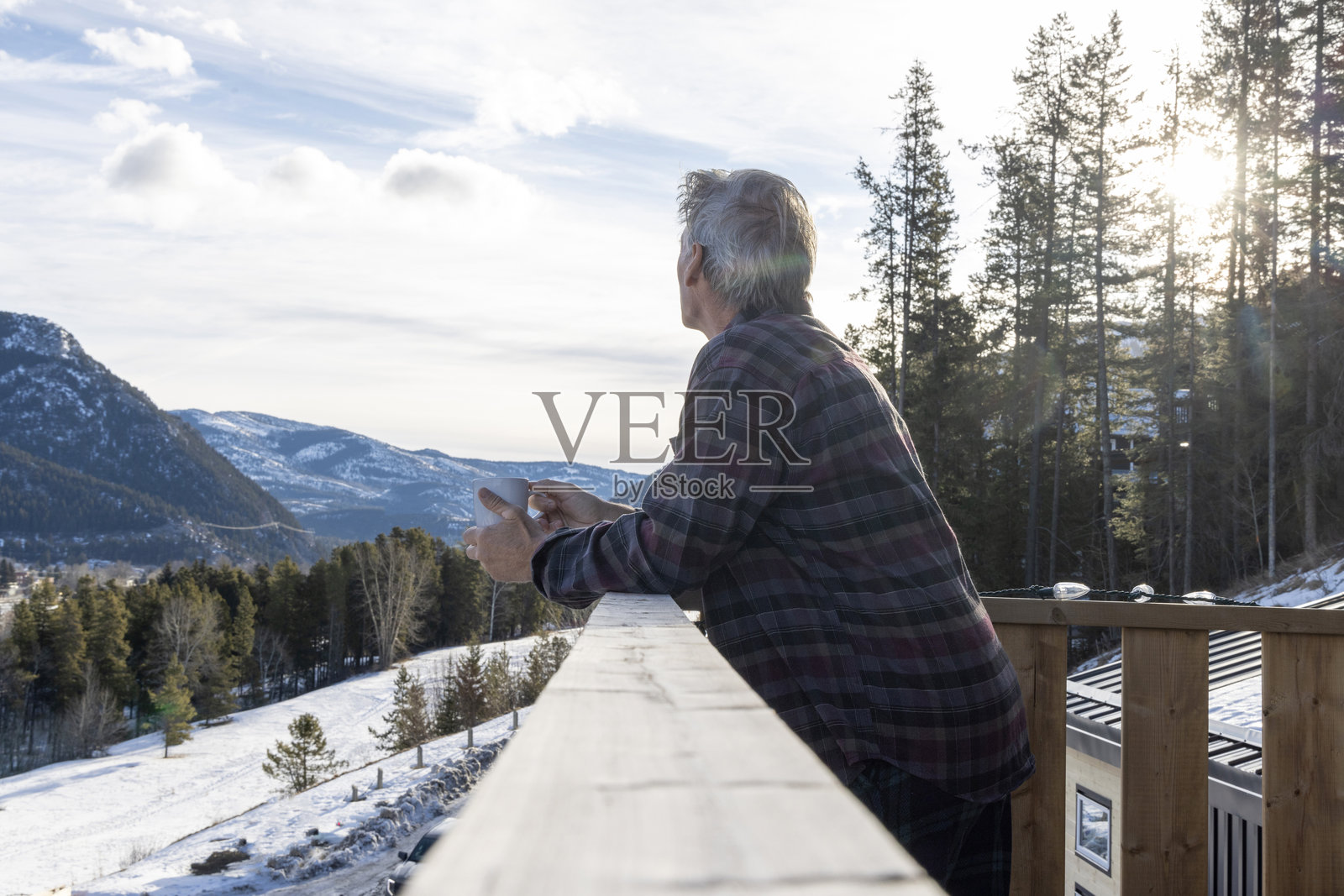 成熟男性在冬季日出时在甲板上享受热饮照片摄影图片
