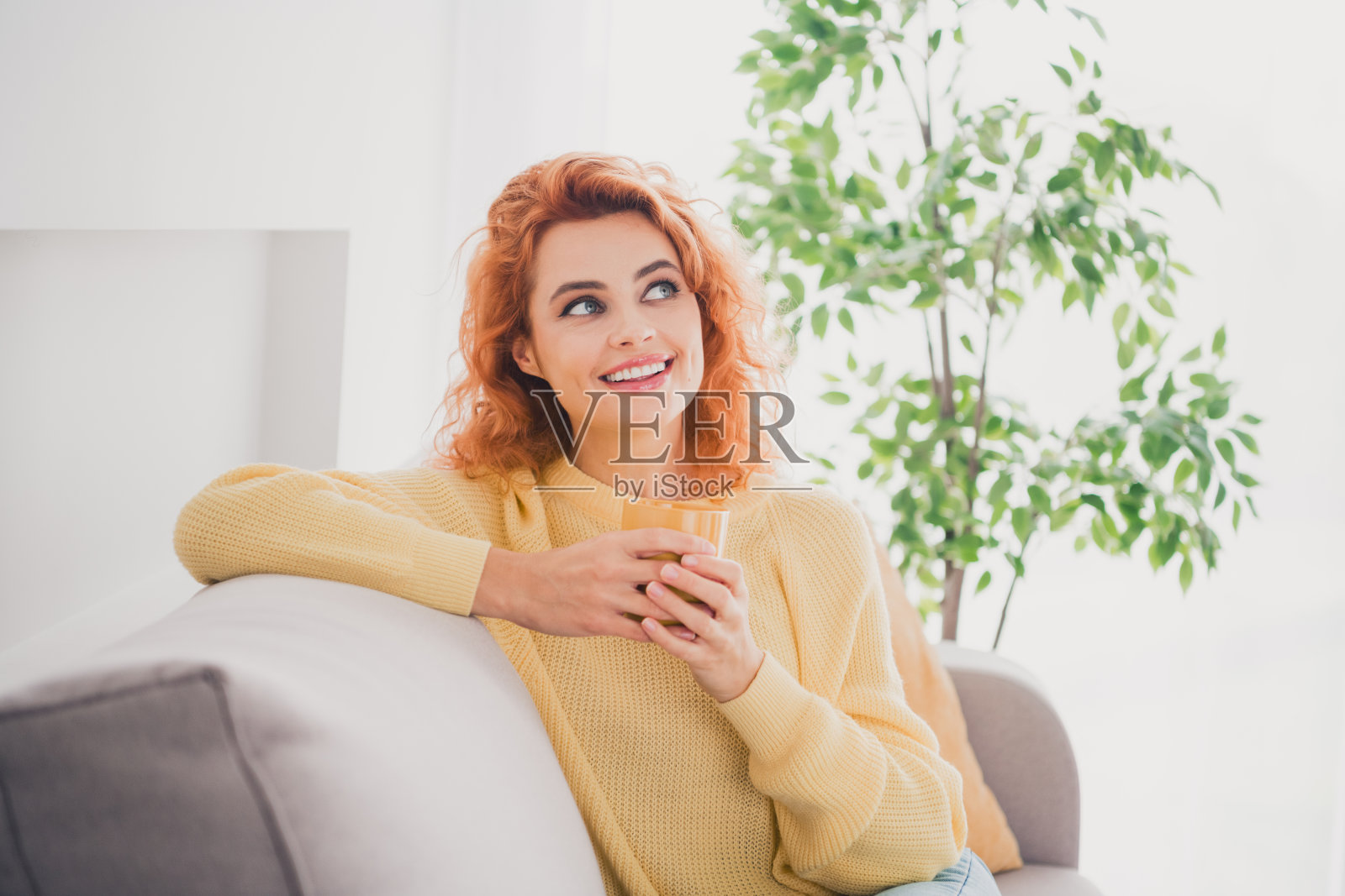 穿着黄色连衣裙的闪亮梦幻女孩在室内公寓房间微笑着喝饮料照片摄影图片