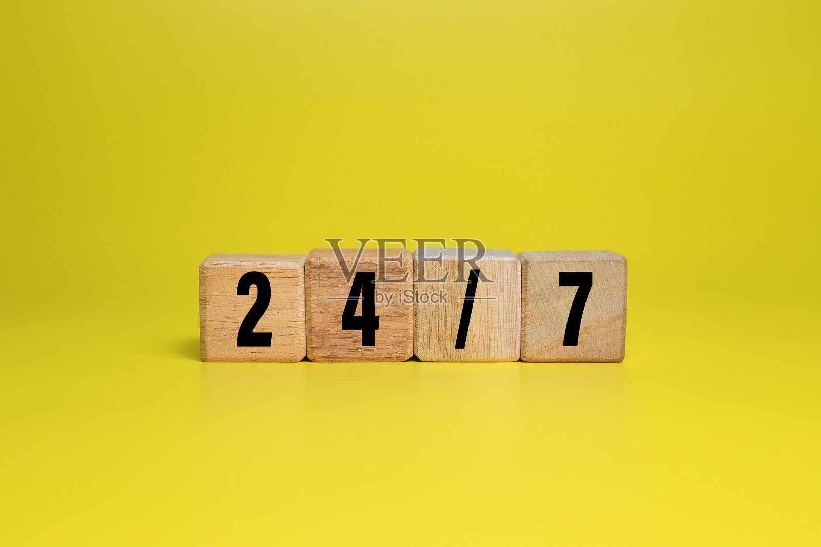 木块上孤立的24/7字母符号，背景为黄色照片摄影图片
