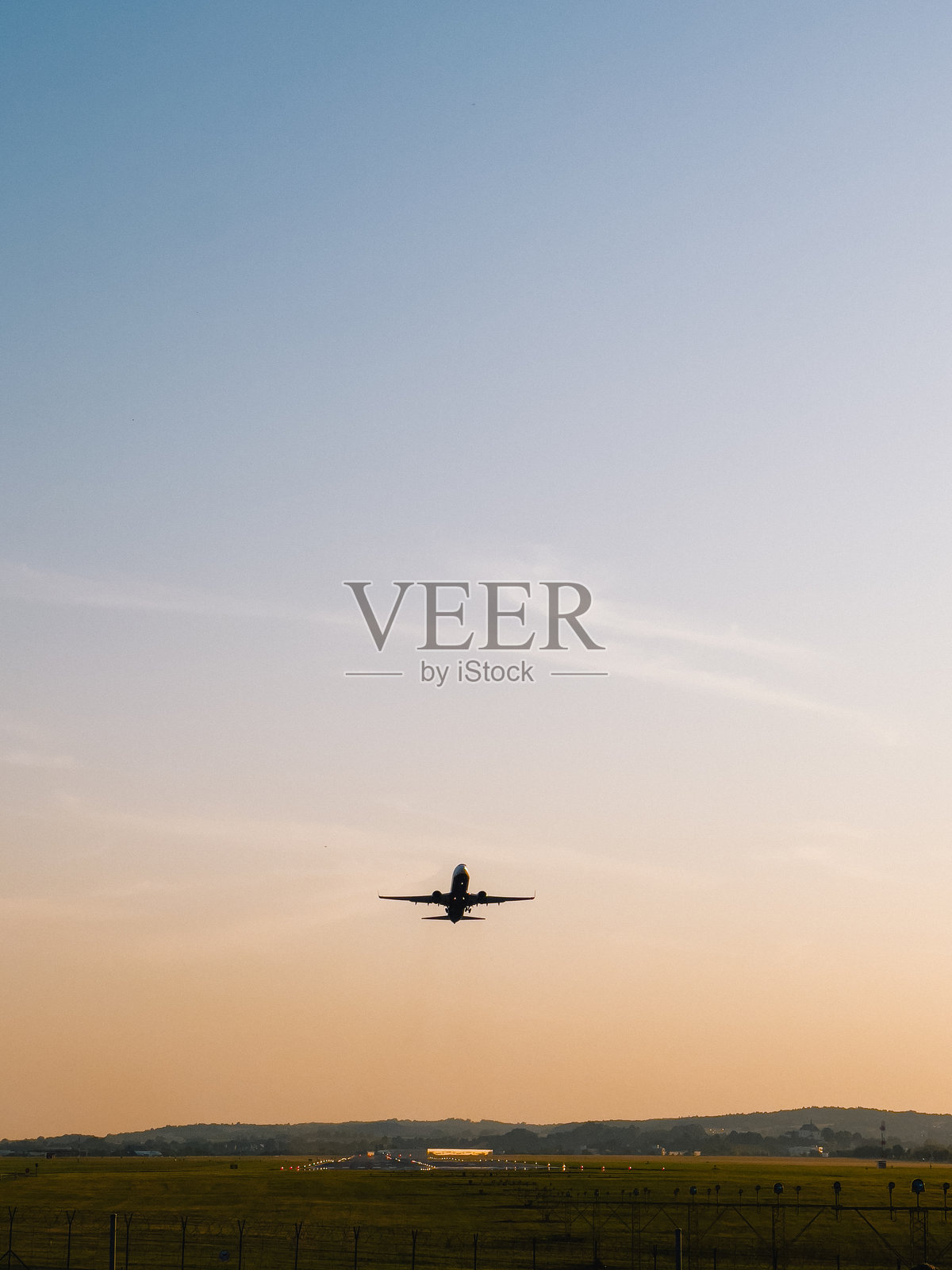 喷气式飞机在金色时光的机场跑道上起飞，背景是晴朗的天空和宁静的风景，展现了航空旅行和航空工业的美丽景观。商业航空旅行照片摄影图片