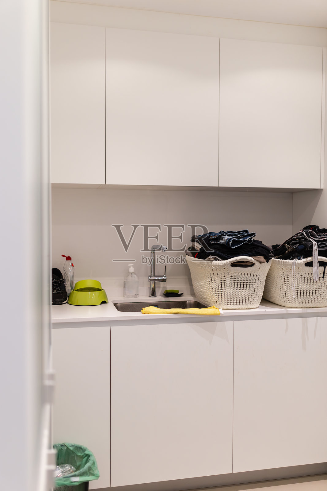 洗衣房配有橱柜、水槽和水龙头，以及干净的衣物篮子照片摄影图片