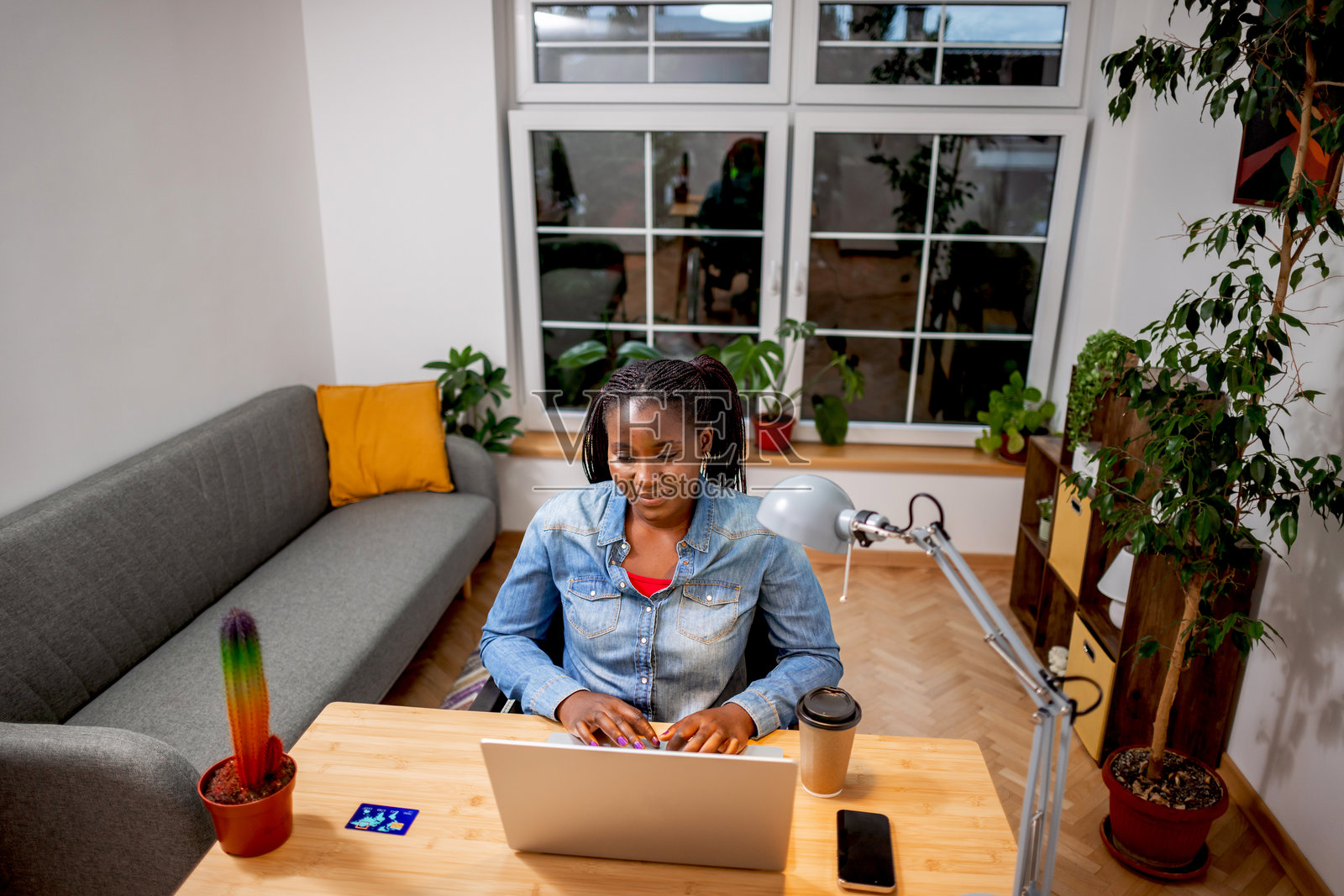 在现代公寓里，编辫子的女性正在用笔记本电脑冲浪照片摄影图片
