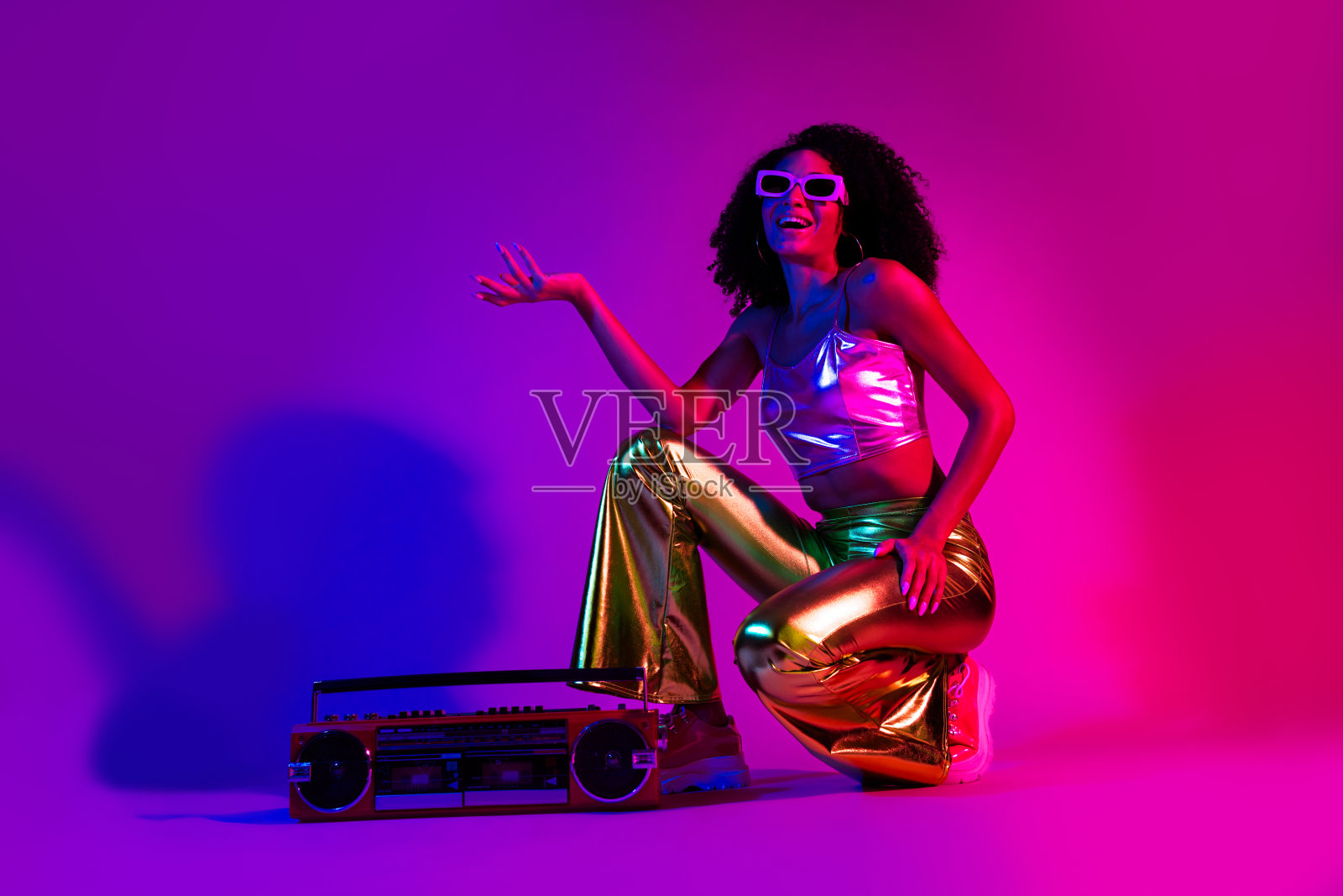 时尚年轻女性穿着闪亮的服装，站在复古立体声前，背景是充满活力的霓虹灯，享受着迪斯科之夜的欢快氛围。照片摄影图片