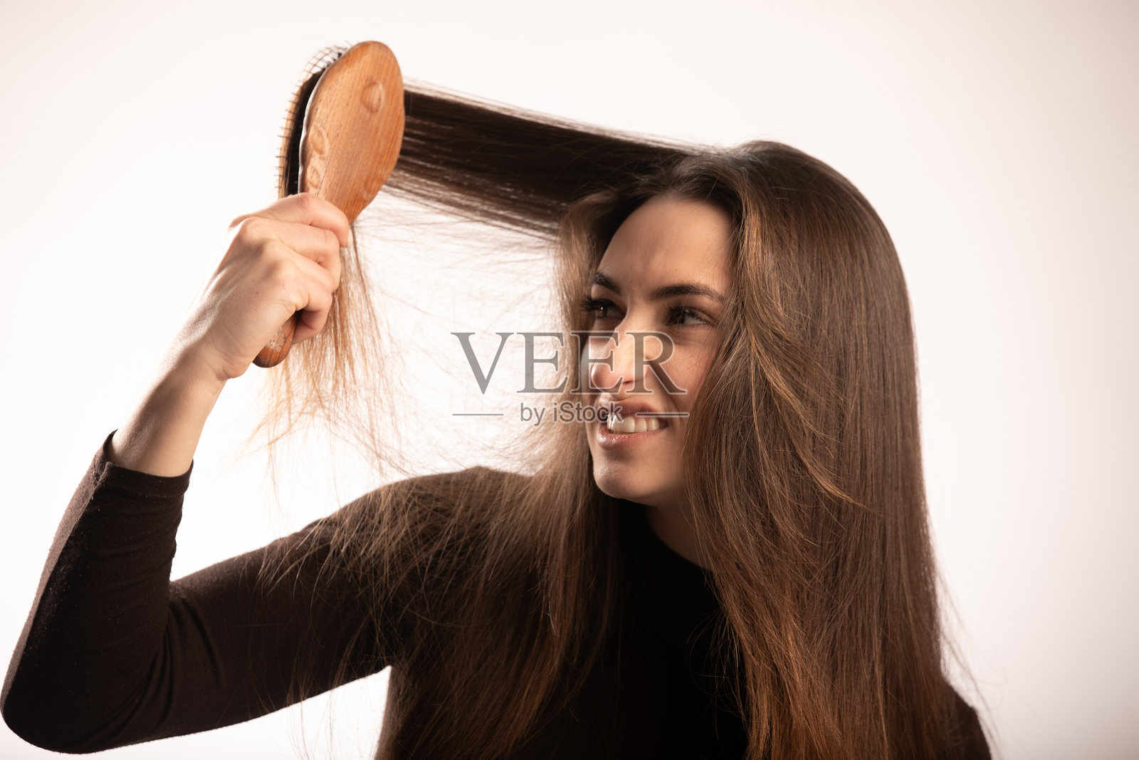 沮丧的长直发棕发女孩正在看着并梳理她的头发照片摄影图片