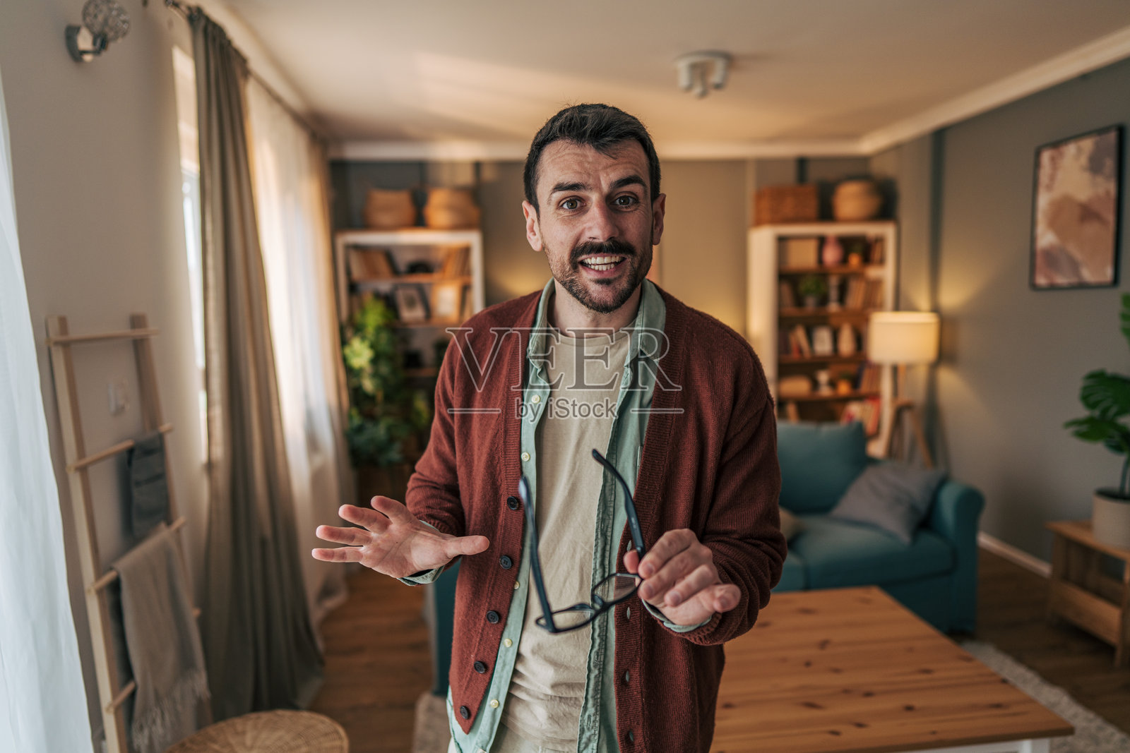 年轻男子在家中进行视频通话并解释某件事情照片摄影图片