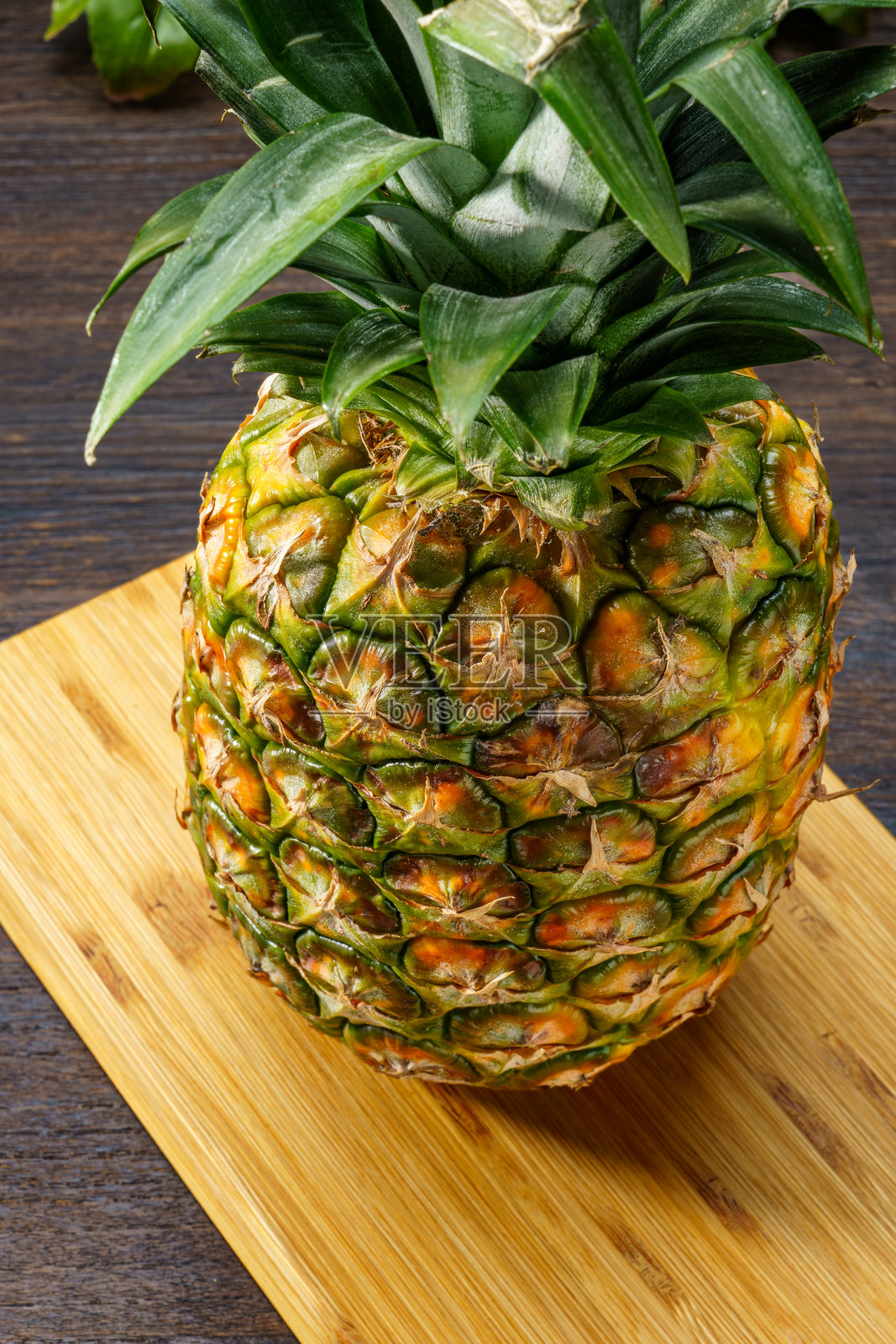 新鲜菠萝和木桌上的切菜板照片摄影图片