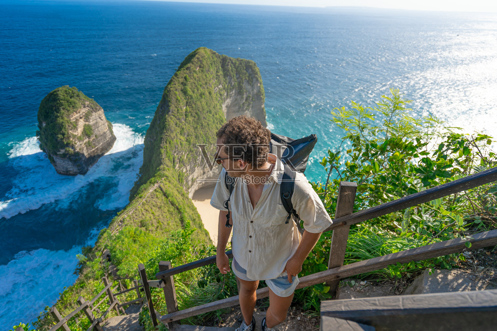 男性游客在印度尼西亚努沙佩尼达岛的凯灵金海滩游玩。攀爬台阶小径到达顶部。照片摄影图片