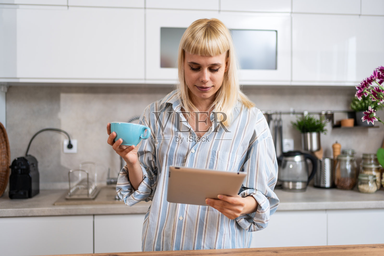 无聊。年轻美丽的女商人开始她的假期，感到无聊，不知道在空闲时间该做些什么。女性站在家里的厨房里，不知道该做什么。照片摄影图片