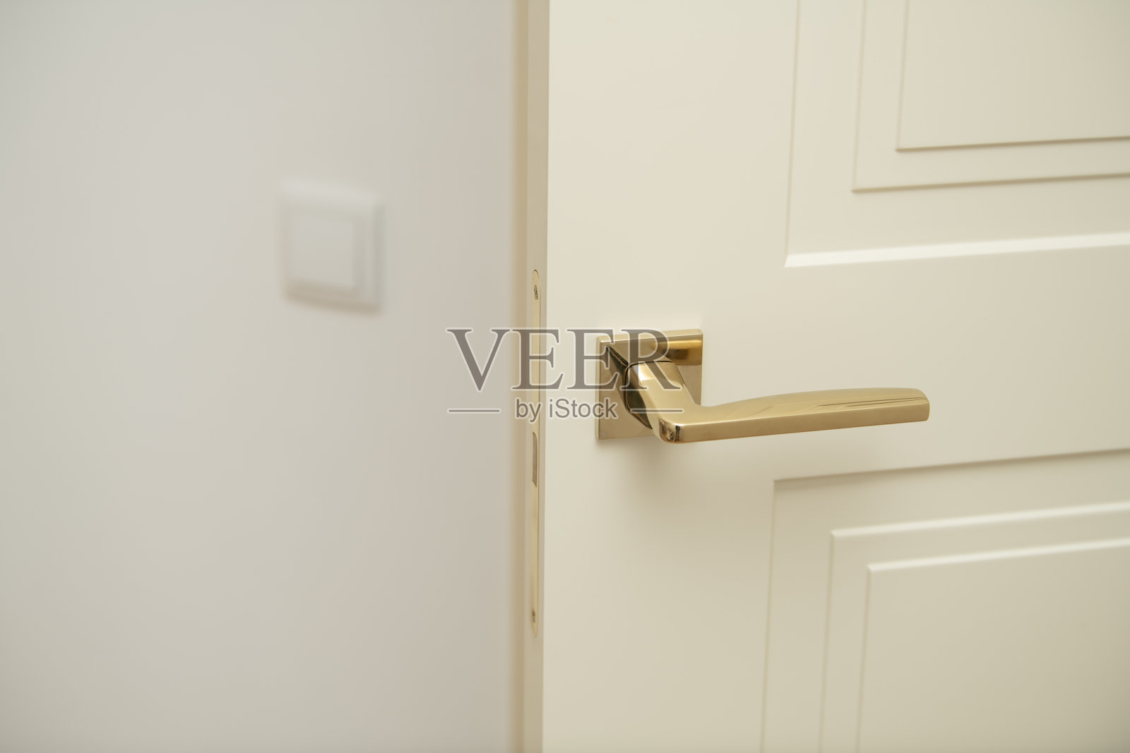 一个时尚的门把手特写，位于奶油色的门上，强调流畅的线条和现代美学，背景是一个光线充足的室内空间。照片摄影图片