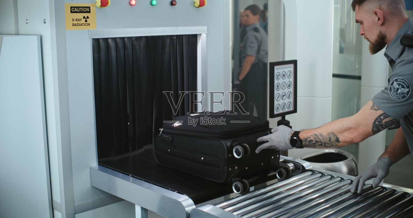 机场安检：TSA工作人员将行李和个人物品放入X光金属探测器中照片摄影图片