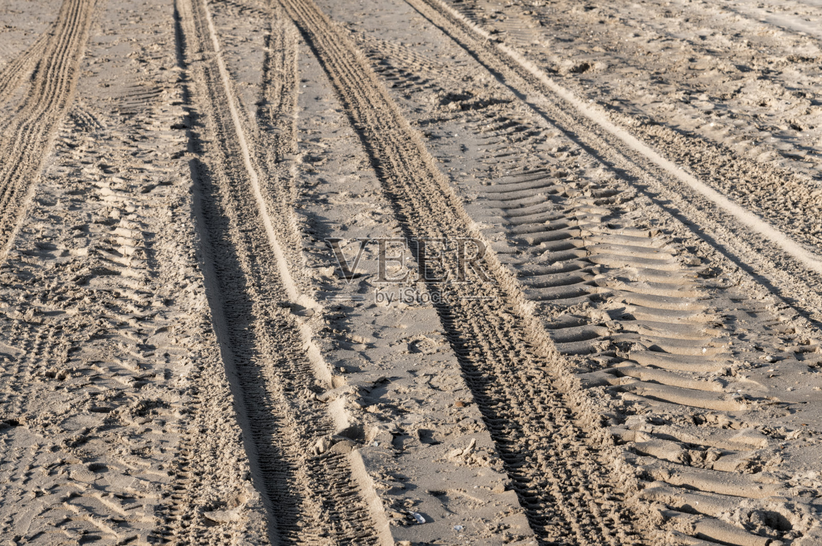 轮胎印在沙滩上交错，形成引人入胜的图案照片摄影图片