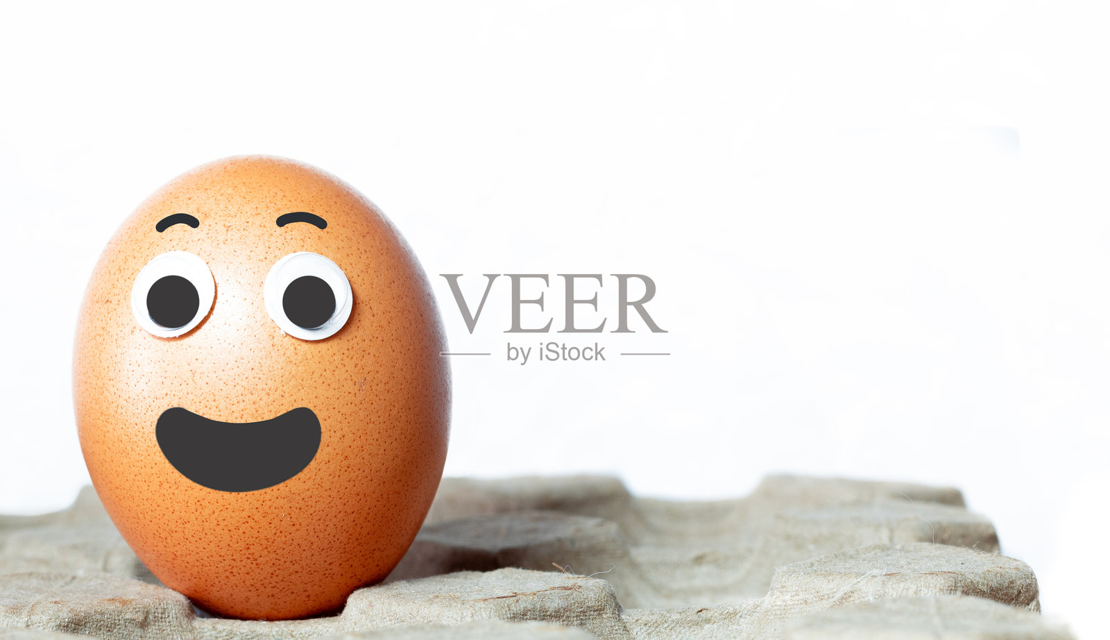 白色背景上的友好姿态的鸡蛋。微笑的鸡蛋孤立在蛋 carton 上。带有留白的图像。照片摄影图片